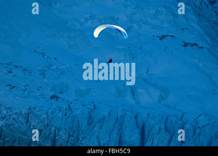 Pilota di parapendio volare su un ghiacciaio sui fianchi del Les Bossons ghiacciaio sul Mont Blanc. Foto Stock