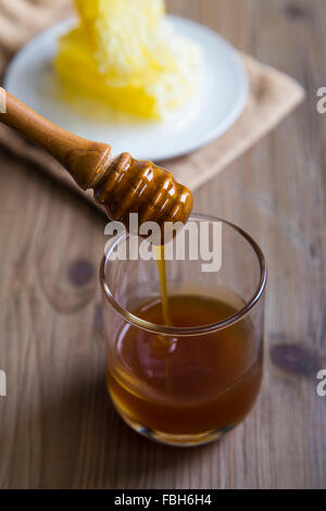 Il miele il gocciolamento da un miele di legno bilanciere Foto Stock