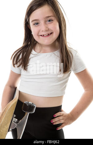 Cheeky giovane ragazza con il suo skateboard con una mano e con il suo altro sulla sua anca. Foto Stock