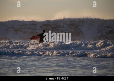 Surfer circa alla paletta in high surf. Fotografato a Rockaway Beach, Queens, a New York nel mese di ottobre 2015. Foto Stock