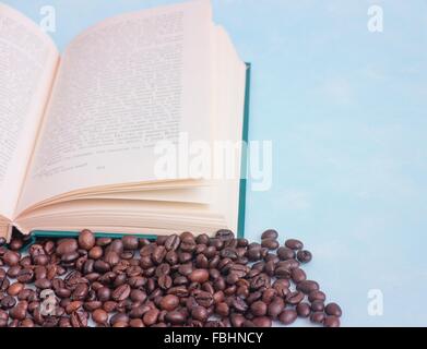 Chicchi di caffè tostati sullo sfondo di un libro aperto Foto Stock