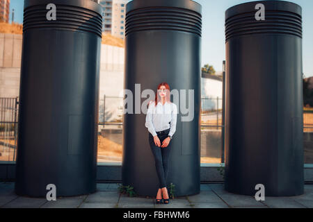 Moda redhead giovane donna in occhiali da sole all'aperto a piedi sulla strada Foto Stock