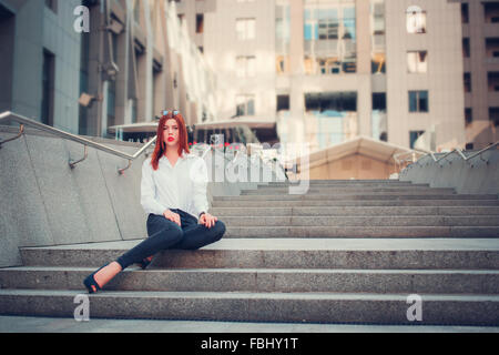 Moda redhead giovane donna in occhiali da sole all'aperto a piedi sulla strada Foto Stock