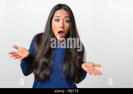 Giovane donna scrollare le spalle e gesticolando con la mano con la sua bocca aperta in segno di protesta come lei dimostra la sua ignoranza o inn Foto Stock
