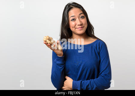 Sano giovane donna tenendo un grande lo zenzero e sorridente nella fotocamera Foto Stock