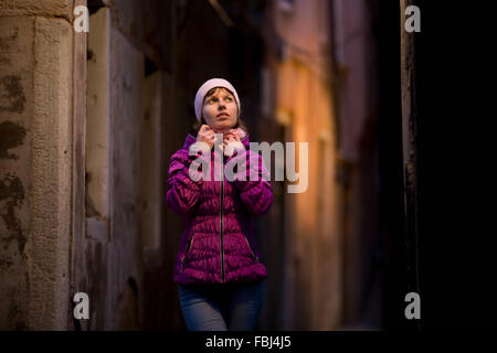 Yong femmina di camminare sulla strada di notte fredda in abiti casual, solitario, avvolgere nella camicia Foto Stock