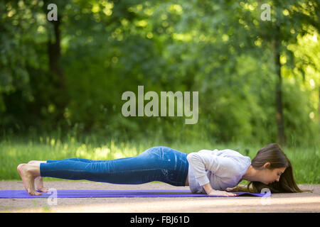 Bella giovane sportivo da donna che lavorano fuori sulla strada facendo crossfit training di forza, sul tappetino blu in park alley, push-up, chatu Foto Stock