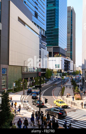 Giappone, Osaka Umeda. Vista lungo la strada principale e la base di tre grandi torre ufficio blocchi. Le persone e le automobili, diurno, sole brillante. Foto Stock