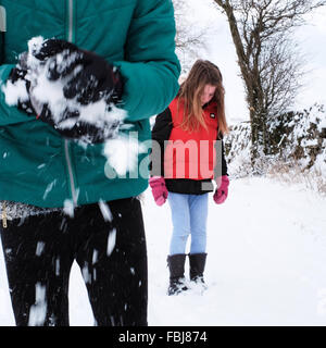 Due ragazze vestite caldo nella neve giocando, rendendo snowballs Foto Stock