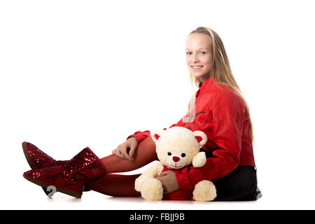 Ritratto di felice casual bella ragazza adolescente in rosso giacca di pelle seduta con Teddy bear, amichevole e sorridente guardando è venuto Foto Stock