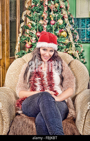 Giovane bella ragazza, Donna in una bellissima camera con un albero di Natale, femmina con doni, albero verde, donna felice anno nuovo, Sittin Foto Stock