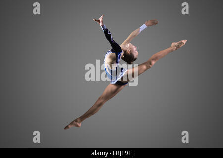 Bella giovane montare ginnasta donna in blu abbigliamento sportswear, performing art ginnastica elemento, jumping Foto Stock