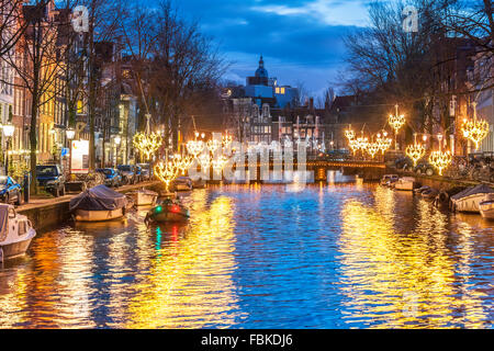 Amsterdam Herengracht Canal in inverno con luci stagionale e la piccola barca al tramonto. Amsterdam Light Festival Foto Stock