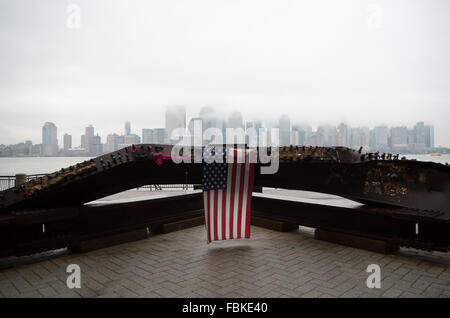 Memorial a 9/11 attentato terroristico di Jersey City waterfront con la skyline di New York in background coperta da basse nubi. Foto Stock