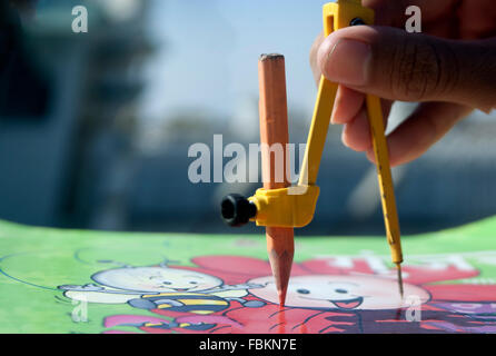 Un ragazzo caucasico utilizzando un divisore per disegnare un concetto geometrico. Foto Stock