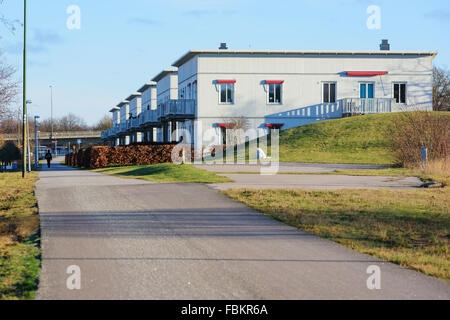 Karlskrona, Svezia - 13 Gennaio 2016: una fila di moderni edifici residenziali con un passaggio pedonale di fronte. Una persona a piedi lungo il Foto Stock