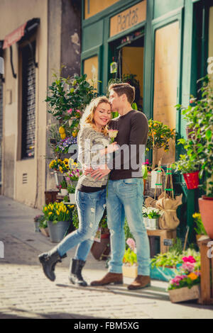 Giovani caucasici bella giovane in amore baciare sulla strada per celebrare il giorno di San Valentino con rose dono che mostra la loro passione Foto Stock