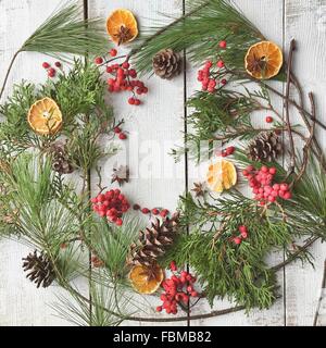 Disposizione di festa in forma ghirlanda di pigne, frutta, bacche e pino per Natale Foto Stock