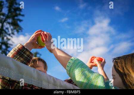 Due bambini di passare le palline da tennis sopra la parte superiore della rete Foto Stock