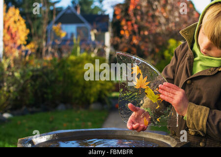 Giovane ragazzo al di fuori di trattenere foglie congelate in ghiaccio Foto Stock