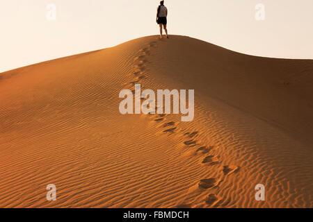 Donna in piedi su una duna di sabbia nel deserto, Dubai, UAE Foto Stock