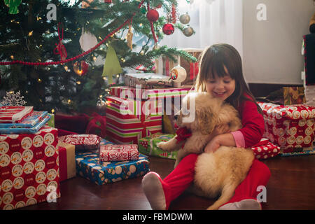 Ragazza abbracciando il golden retriever cucciolo di cane a Natale Foto Stock