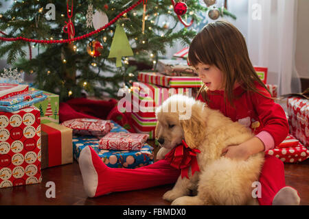 Ragazza abbracciando il golden retriever cucciolo di cane a Natale Foto Stock