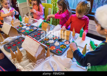 Gruppo di bambini decorare Gingerbread case a Natale Foto Stock