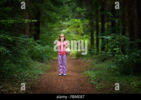 Ragazza in piedi sul sentiero nel bosco Foto Stock