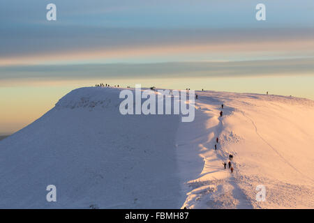 La mattina presto walkers scalare il vertice invernale di Pen y ventola nel Parco Nazionale di Brecon Beacons, Galles Foto Stock