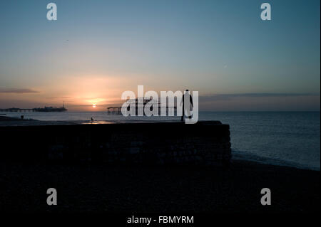 Uomo in piedi su groyne, silhouette, sunrise Foto Stock