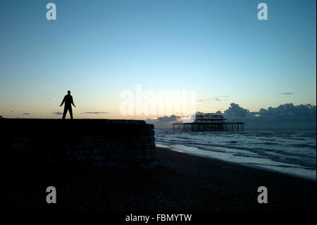 Uomo in piedi su groyne, silhouette, sunrise Foto Stock