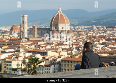 Un giovane uomo godendo la vista di Santa María del Fiore da Piazzale Michelangelo, Firenze, Toscana, Italia. Foto Stock