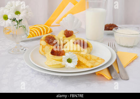 La prima colazione con pancake, confettura di albicocca e latte e arance Foto Stock