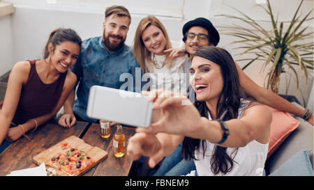 Gruppo di amici prendendo selfie su uno smart phone. Giovani uomini e donne che prendono un autoritratto sul telefono cellulare. I giovani su rooft Foto Stock