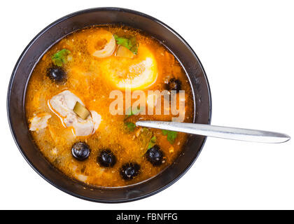 Vista superiore del Solyanka tradizionali russe e piccante sour zuppa di pesce nel recipiente con cucchiaio isolati su sfondo bianco Foto Stock