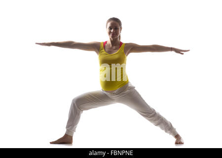 Per tutta la lunghezza della silhouette felice giovani incinte modello di fitness in sportswear fare yoga, Pilates Formazione, Guerriero II la postura Foto Stock