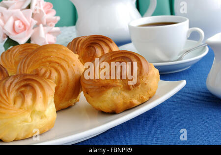 Eclairs close-up su una piastra con una tazza di caffè Foto Stock