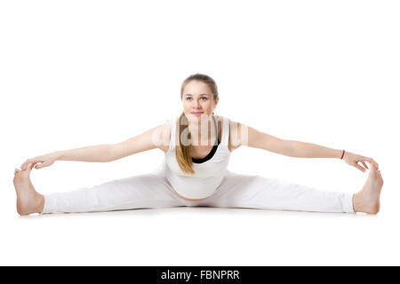 A piena lunghezza Ritratto di giovane sorridente incinta modello di fitness in sportswear, fare yoga, Pilates Formazione, Wide-Angle seduto Foto Stock