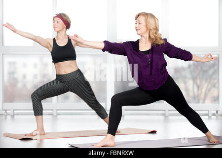 Fitness, stretching pratica, gruppo di due attraenti sorridenti montare donne mature di lavoro nel club sportivo, facendo lunge Foto Stock