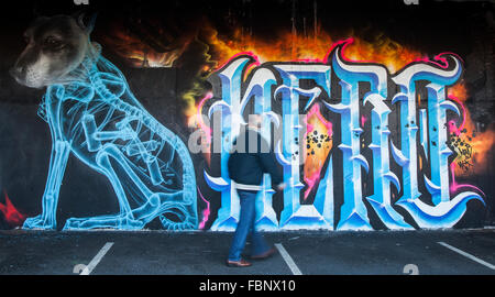 Pedone passato walking street art graffiti dipinti a muro, decorazione. Graffiti in centro città parcheggio auto, Blackpool, Lancashire, Regno Unito Foto Stock