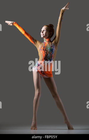 Bella ginnasta felice atleta ragazza adolescente che indossa la ballerina colorata leotard lavorando fuori, ballare sulla tiptoes ponendo Foto Stock