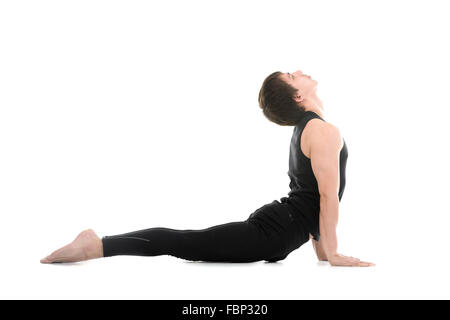 Profilo del giovane sportivo uomo che lavora fuori, facendo esercizi per la colonna vertebrale flessibile, Yoga asana da Surya Namaskar, Sun Salutation Foto Stock