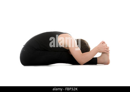 Atletica Giovane uomo fa esercizi yoga, seduti piegare in avanti pone (intenso tratto dorsale), Paschimottanasana, stiramento della colonna vertebrale Foto Stock