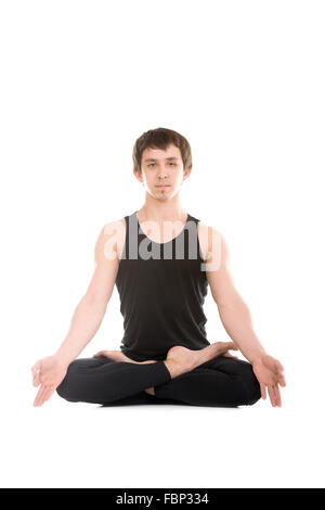 La meditazione, sportivo serena giovane uomo in seduta con le gambe incrociate lotus Yoga asana Padmasana con le dita in yogic gesto Chin Mudra Foto Stock