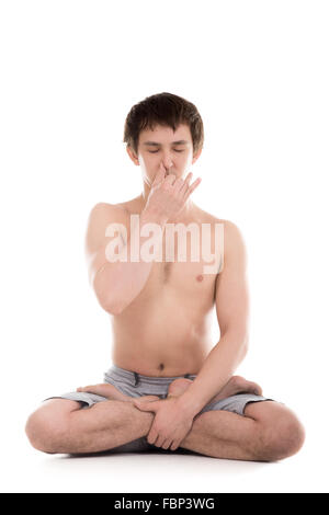 Bello serena sportivo giovane uomo meditando, narice alternativa tecnica di respirazione, in seduta con le gambe incrociate yoga lotus pongono Foto Stock