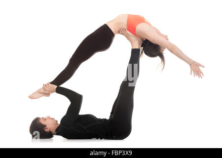 Coppia sportiva su sfondo bianco facendo acroyoga, fitness o pilates pratica in coppia, yoga con partner, high Flying Whale Foto Stock