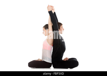 Due sportivi la pratica dello yoga con partner, seduta con le gambe incrociate nella posizione del loto, facendo esercizi di stretching per la colonna vertebrale. Foto Stock