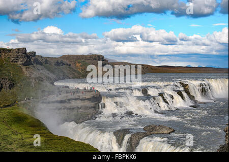 Cascata Gullfoss durante il tour del cerchio d'oro in Islanda, una destinazione turistica e una meraviglia della natura con una doppia cascata. Si trova nel sud dell'Islanda, sul fiume Hvítá Hvita (bianco), alimentato dal ghiacciaio Langjökull Langjokull. La nebbia si innalza oscurando le persone in lontananza. Foto Stock