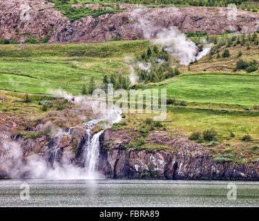 A nord-est dell'Islanda, dell'Islanda. 1 agosto, 2015. Nel nord-est dell'Islanda, cascate vuota nel fiordo Eyjafjordur su scogliere vulcaniche come il fumo sale dal vapore caldo molle, vicino al porto di Akureyri, Islanda il secondo più grande area urbana, un importante centro di pesca dove il turismo è diventato un settore in crescita dell'economia. © Arnold Drapkin/ZUMA filo/Alamy Live News Foto Stock